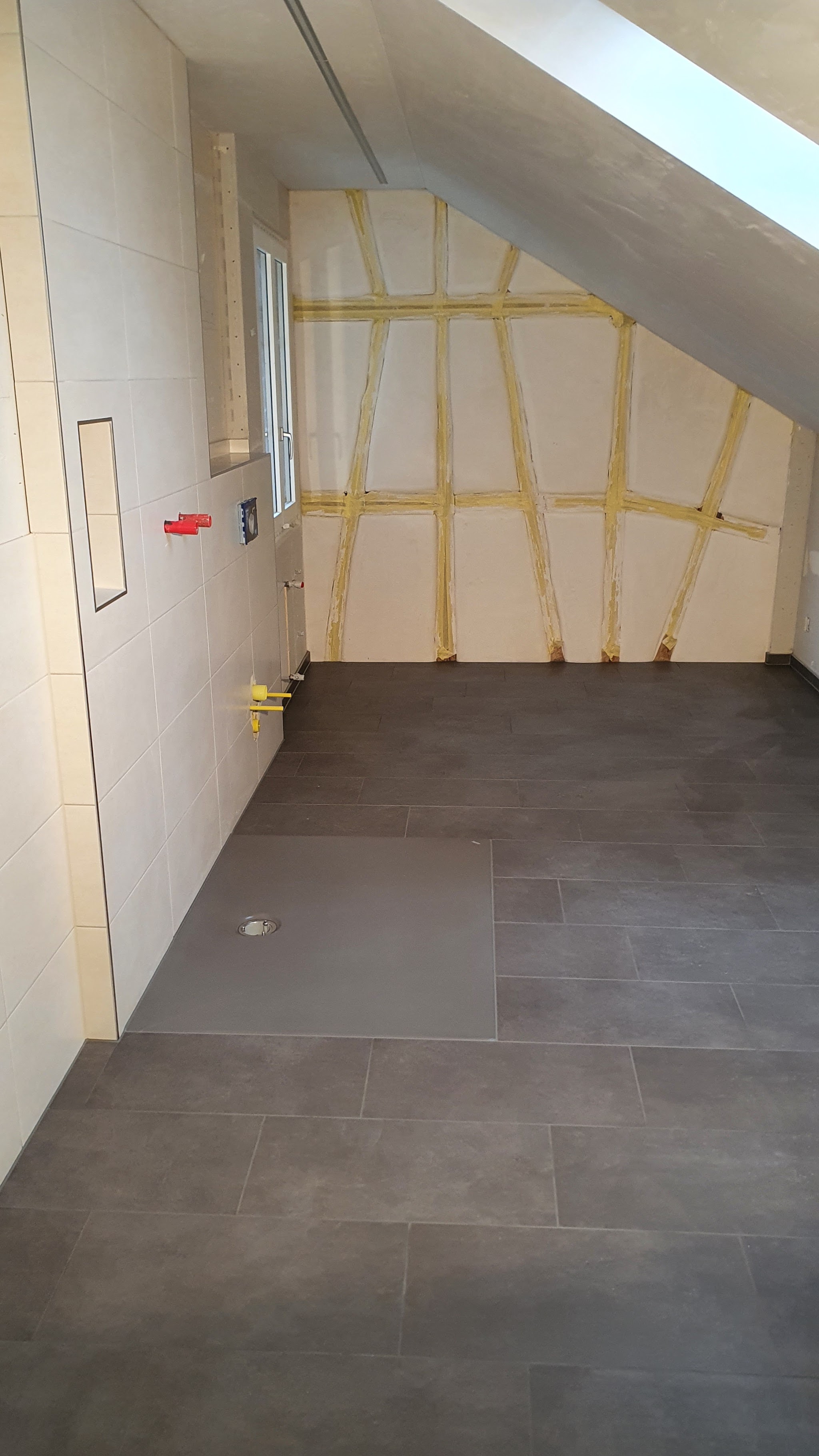 Dusche unter der Dachschräge mit dunklen Bodenplatten und gefliesten Wänden