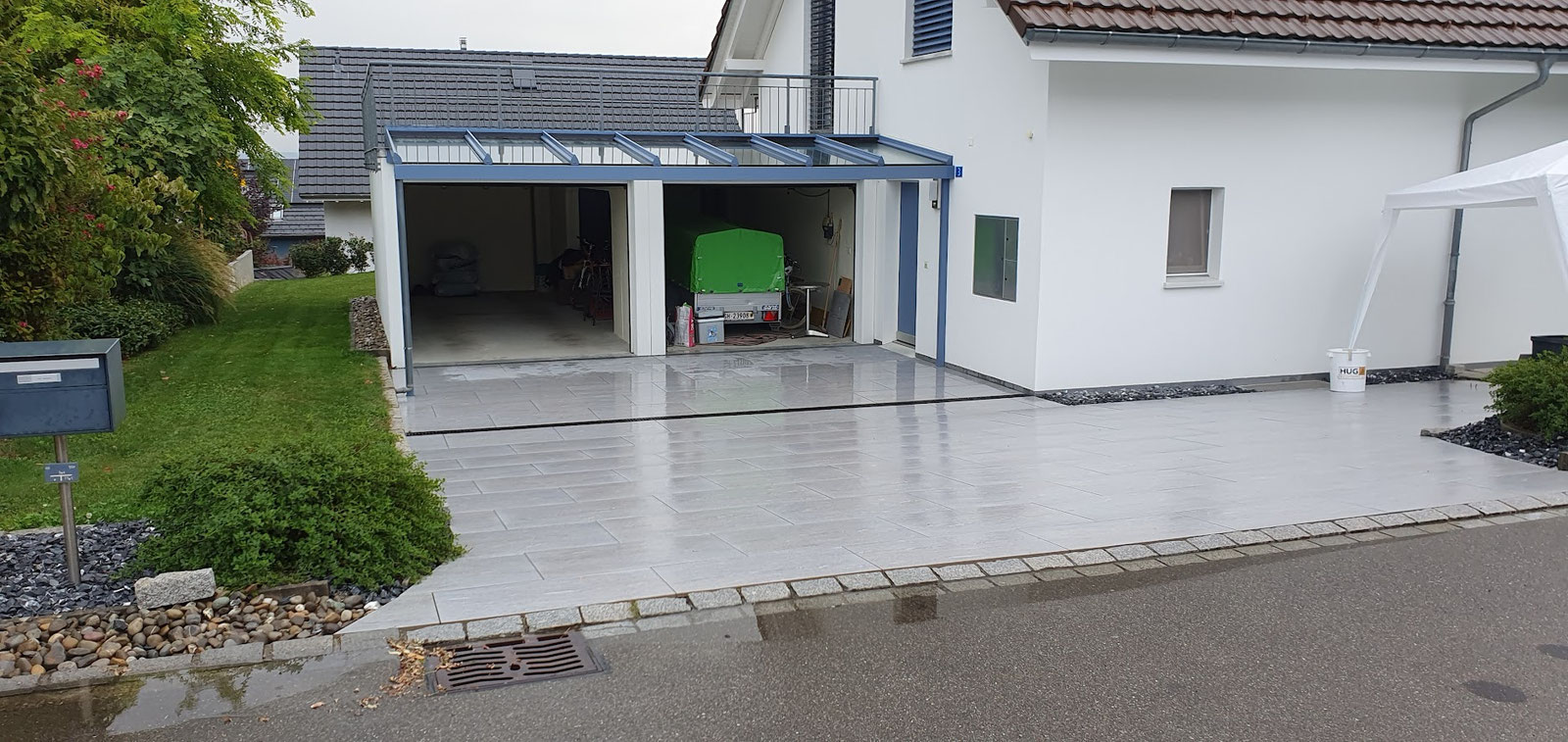 Plattenbelag vor Garage und Eingang eines weissen Hauses