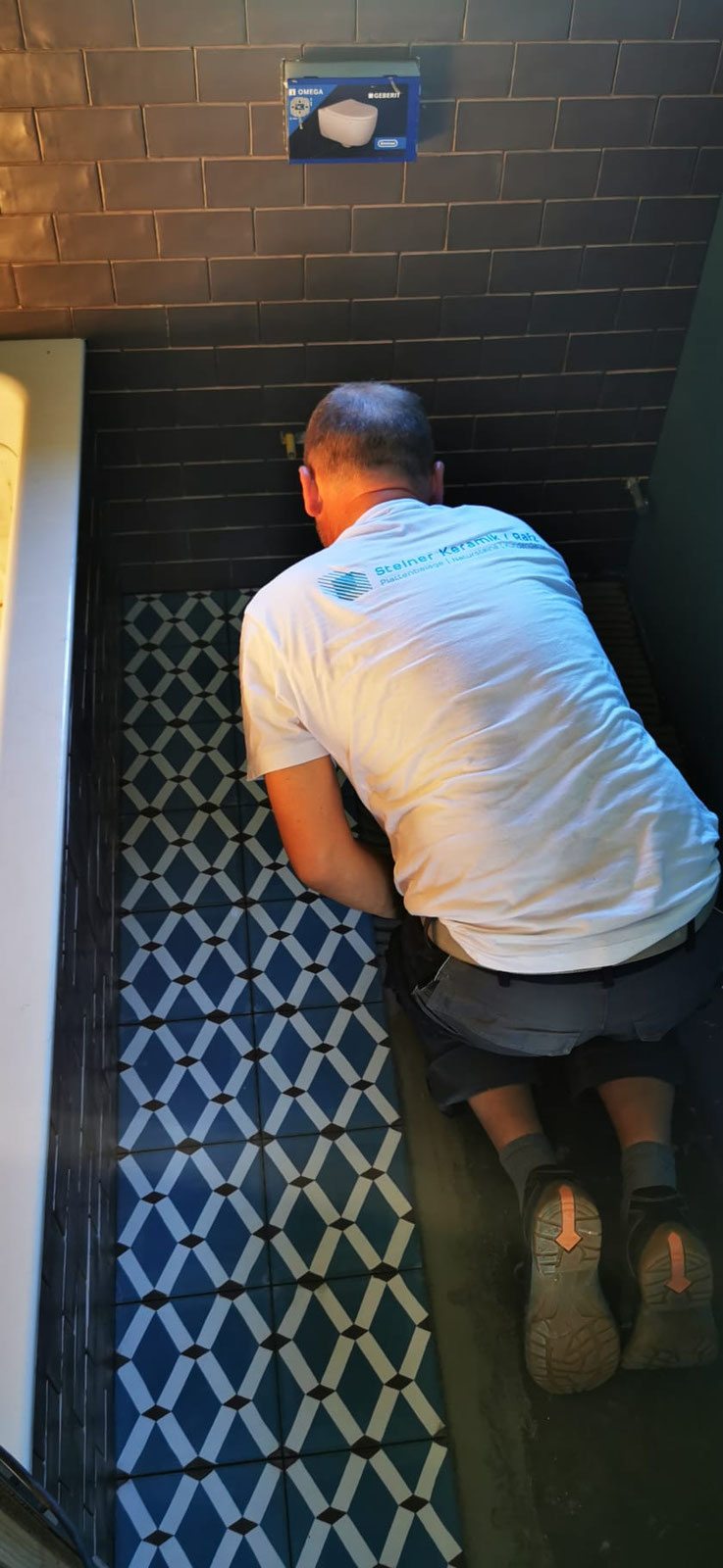 Plattenleger verlegt einen blau gemusterten Duschboden
