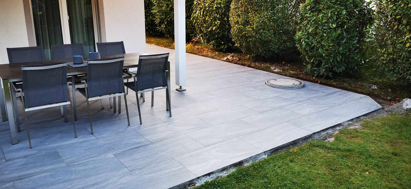 Terrasse mit Gartenmöbeln auf grauen Platten