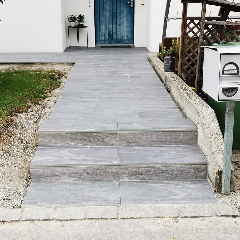Zugang mit Plattenstufen zur blauen Haustür